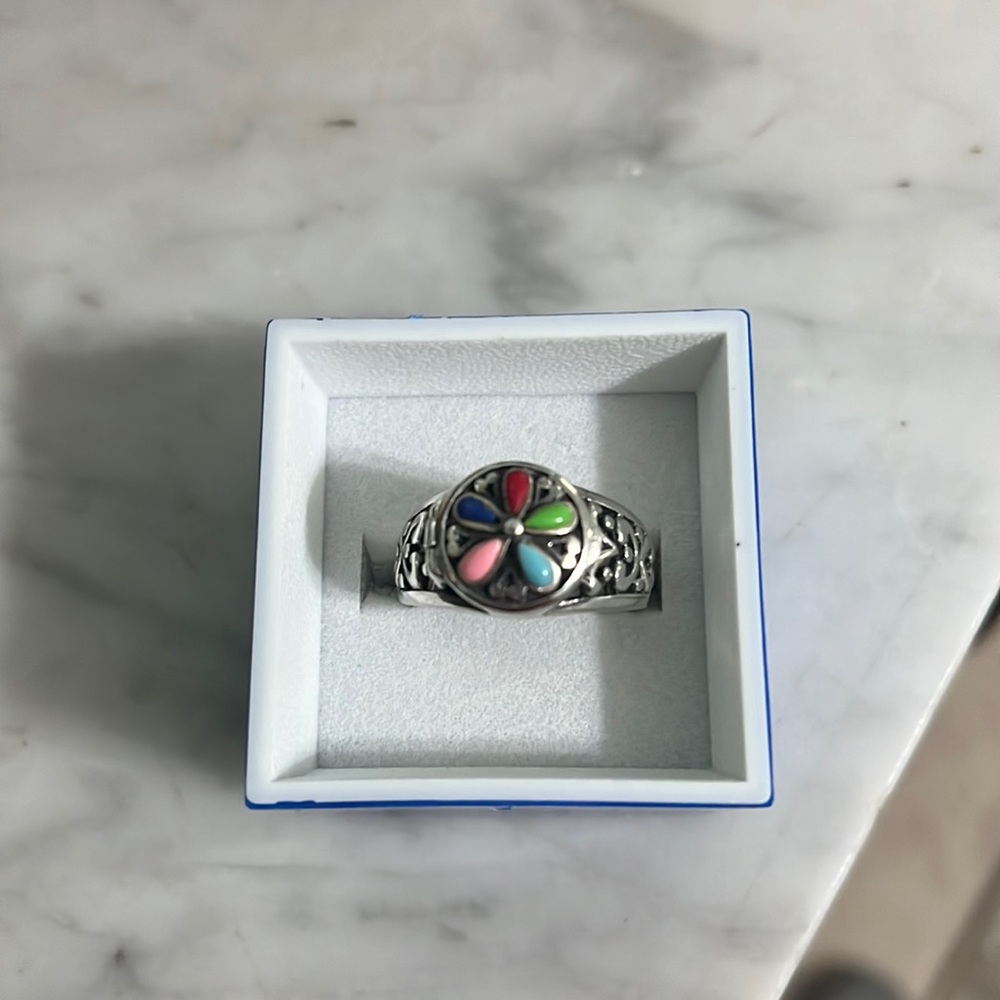 Silver ring (sterling) with multicolored stones on top. Opens secret compartment